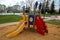 A children`s slide of yellow red blue color in a city park on a clear sunny day. Playgrounds, toys