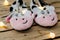 Children`s socks sneakers in the form of spotted cows on a wooden background with Christmas lights