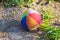 Children\'s soft fabric and striped multi-colored ball about the gray stones round the foot of the alpine hills in the green grass.