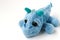 Children`s soft toy blue dragon is located on a white background