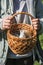 Children`s teenage hands hold a wicker brown hand-made basket with blue textured Easter eggs and a white plastic rabbit