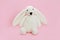 Children`s toy white fluffy plush rabbit with long ears on pink background
