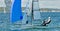 Children sailing racing small sailboat with a blue spinaker on a coastal lake. Commercial use photo