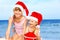 Children in santa hat playing on beach.