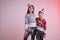 Children in santa sweaters and hats stained in synthetic snow isolated over pink background, brother hugs his sister