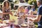 Children Serving On Cake Stall At Busy Summer Garden Fete