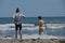 Children, siblings playing on the sea shore. They jumping in the waves