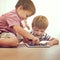 Children, siblings and tablet on a floor with cartoon, gaming or streaming movie at home. Digital, learning and boy kids