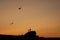 Children silhouettes with kite flying on sunset landscape with rocks