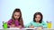 Children sisters, decorate the picture with pencils. White background. Slow motion