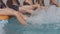 Children sit on the edge of the pool and splash their feet. Legs close up. Boys and girl in the pool, on vacation