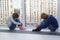 children sit on floor by window and cannot go outside because of quarantine. little blond boy and girl have their hands clasped