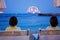 Children, sitting on beach, watching lighted ship in the ocean