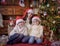 Children sitting with mother under Christmas tree in hats