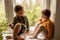 Children sitting on windowsill and waiting for someone comming. Two brothers, friends. Cute preschool kids alone at home