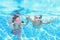 Children swim in swimming pool underwater, happy active girls have fun under water, kids fitness and sport on family vacation