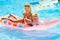 Children swimming on inflatable beach mattress.