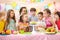 Children at table celebrating birthday holiday. Kids blows together candles on festive cake