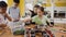 Children at the table in a class at a robotics lesson assemble modules for moving robots with hands and screwdrivers and