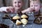Children taste finished cupcakes sitting behind wooden surface