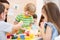 Children with teacher play colorful clay toy in daycare