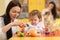 Children with teachers play with color wooden puzzle in a montessori classroom