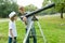 Children teenagers in the park looking through a telescope