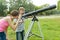 Children teenagers with telescope look at the sky in nature