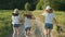 Children three girls in hats holding hands running back along the rural country road