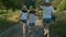 Children three girls in hats holding hands running back along the rural country road