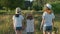 Children three girls in hats holding hands walking back along the rural country road