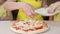 Children together with Mom cook pizza close up. The girls sprinkle pizza with cheese close-up, and help their mother