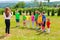 Children with tutor play outdoor on the green lawn