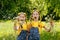 Children walk in a meadow with dandelions. Girls blow on flowers in the spring in the park. Two sisters in yellow T-shirts and two