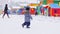 Children walk on playground in snowy yard near kindergarten