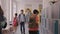 Children walk in school hallway, boy closes his locker. Children sit together