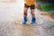 children wearing rain boots and jumping in puddle on rainy