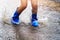 children wearing rain boots and jumping in puddle on rainy