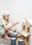 Children at work: The girl neatly paints the facade of the doll house with a small tassel in white.