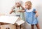 Children at work: Two girls sisters paint the roof of the doll house in white. The youngest girl intently makes smears