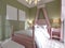 Childrens bedroom with a large pink bed and a canopy over, pistachio-colored walls