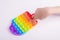 Childrens hand playing with rainbow fidget toy pop it isolated on the white.