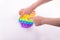 Childrens hand playing with rainbow fidget toy pop it isolated on the white.