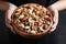 Childrens hands holding a wooden bowl with mixed nuts. Healthy food and snack. Walnut, pistachios, almonds, hazelnuts and