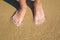 Childrens legs close-up on the edge of the water sandy beach sea shore