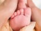 Childrens legs on moms hands. Photo of the feet of a newborn. In the arms of mother