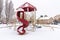 Childrens playground with curvy red slide amid houses on a frosty winter setting