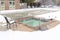 Childrens pool and frozen adult swimming pool surrounded by snow in winter