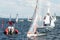 Childrens yacht race starting boat mingling with competing saleb