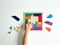 childs hand collects multicolored wooden mosaic on white background. child solves colorful tangram